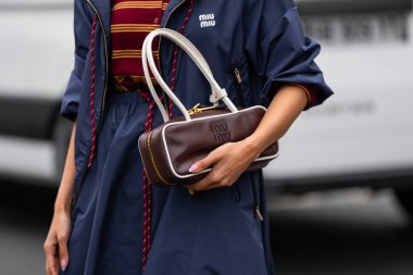 Paris, Fransa - 11 Mart 2025: Kadın Miu Miu kahverengi deri çanta giyiyor, beyaz saplı ve mavi ceketli. Moda blogcusu kıyafet detayları, sokak tarzı.