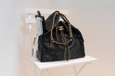 Milan, İtalya - 12 Nisan 2025: Chanel örtülü deri çanta üzerinde altın zincirli logo ayrıntıları lüks butik vitrinlerde beyaz koltuğun üzerinde.