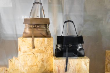 Milan, İtalya - 12 Nisan 2025: Kontrplak şeritlerin üzerine inşa edilmiş Moschino deri çantalar. Kahverengi ve siyah kuşak detaylı tasarım. Stüdyo butik konsepti, modern lüks aksesuarlar..