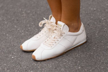 Paris, Fransa - 11 Mart 2025: Sakız tabanı ve altın logolu beyaz deri Miu spor ayakkabılar. Sokak tarzı kıyafet detaylarını kapat.