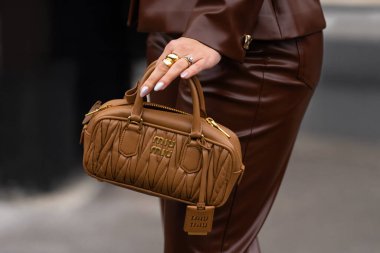 Paris, Fransa - 11 Mart 2025: Karamel, Miu Miu Arcadie marka altın logo ve etiketli, kahverengi deri takımlı mini çanta örttü. Sokak tarzı kıyafet ayrıntıları.