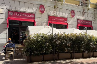 Milan, İtalya - Nisan 07, 2025: Trevesbar caffetteria dışı kırmızı tenteler, teras oturma ve saksı yeşili.