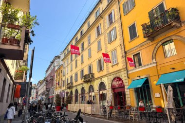 Milan, İtalya - Nisan 07, 2025: Sarı binalar, sokak kafeleri, kalabalık ve bisikletlere Brera Tasarım Bölgesi pankartları.