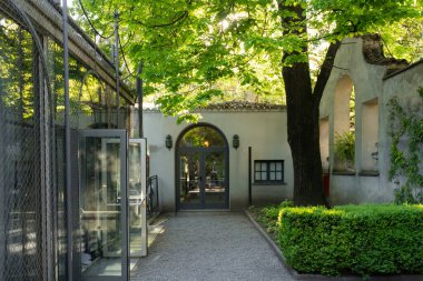 Milan, İtalya - 11 Nisan 2025: Villa Necchi Campiglio. Klasik cam kaldırma, sessiz taş bahçe yolu, yeşil sarmaşık duvar ve sakin bahar bahçesi manzarası..