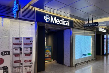 Milan, İtalya - Nisan 07, 2025: Milano merkez tren istasyonunda parlayan eczane haçı ve sağlık posterleri bulunan Piu Medical Parafarmacia eczanesi.