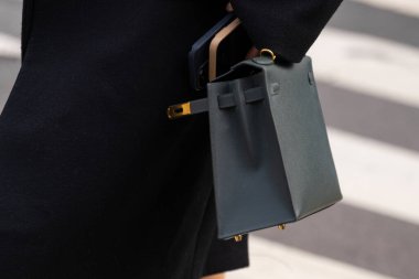 Paris, Fransa - 11 Mart 2025: Kadın koyu yeşil deri Hermes mini çanta ve altın donanım giyiyor. Klasik kutu silueti, siyah paltolu. Sokak tarzı kıyafet ayrıntıları.