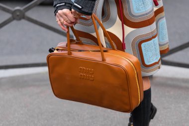 Paris, Fransa - 11 Mart 2025: Kadınlar esmer Miu Miu marka altın fermuarlı bir çanta giyer, eski moda etek ve siyah çoraplar giyerler. Sokak tarzı kıyafet ayrıntıları.