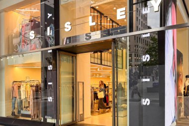 Milan, İtalya - 12 Nisan 2025: SISLEY moda mağazası girişi kıyafet sergileri, mankenler ve alış veriş yapanlar yanımızdan geçiyor. Milan 'da modern perakende tasarımı.