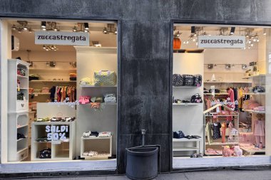 Milan, İtalya - 11 Nisan 2025 Zuccastregata çocuk giyim mağazası. Vitrinlerde bebek kıyafetleri, çantalar, kazaklar ve yüzde 50 indirim tabelası var..
