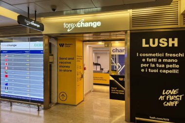 Milan, İtalya - Nisan 07, 2025: Batı Birliği döviz bürosu önx ekran ve Lush kozmetik duvar reklamı ile Milano tren istasyonunda.