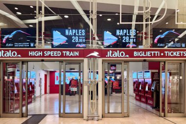 Milan, İtalya - Nisan 07, 2025: Milan 'da Italo tren bileti bölgesi. Napoli terfili kırmızı tabela. Yüksek hızlı seyahat, dijital ekranlar, self servis kioskları.