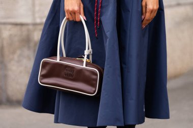 Paris, Fransa - 11 Mart 2025: Miu Miu kahverengi deri çanta fildişi süsleme, altın fermuar ve deniz mavisi etek. Sokak tarzı kıyafet ayrıntıları.