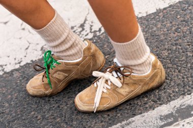 Paris, Fransa - 11 Mart 2025: Kadın şehir kaldırımlarında bej çoraplı yeşil, beyaz ve kahverengi bağcıklı New Balance ayakkabıları giyiyor. Sokak tarzı kıyafet ayrıntıları.