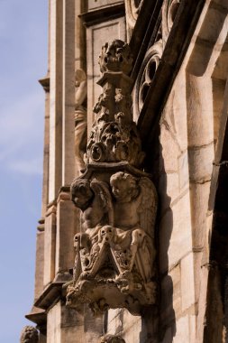 Milan, İtalya - 19.03.2024: Günışığında karmaşık taş oymalarla tarihi gotik mimari, melek heykeli Milan Duomo Katedrali.