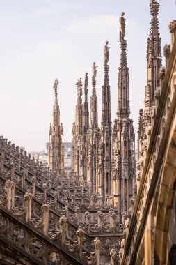 Milan, İtalya - 19.03.2024: Katedral çatılarının Gotik mimarisi açık gökyüzüne karşı Milan Duomo Katedrali.