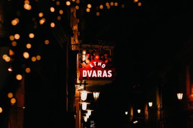 Vilnius, Litvanya - 04.01.2022: Sıcak kentsel bir sokakta aydınlatma işareti olan atmosferik gece sahnesi.