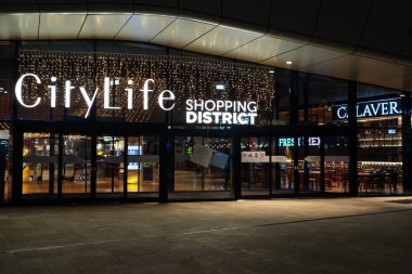 Milan, İtalya - 01.01.2022: Şehir yaşamı alışveriş merkezi girişinin gece görüşü.