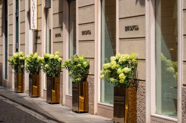 Milan, İtalya - 02.08.2023: Çiçek dekoru ve butik mağazaları olan şık kentsel sokak manzarası.
