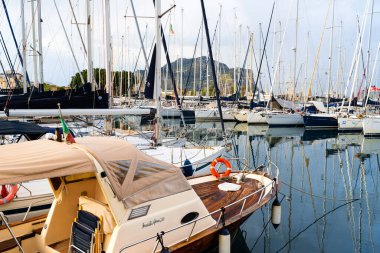 Castellammare del Golfo, İtalya - 05.11.2022: Manzaralı dağ zemininin önüne yanaşmış yelkenli tekneleri ve yatları olan sahne marinası.