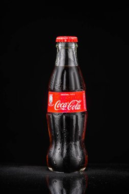 Milan, İtalya - 01.01.2022: İçecek ve içecek temaları için siyah zemin üzerine soğutulmuş Coca Cola şişesi.
