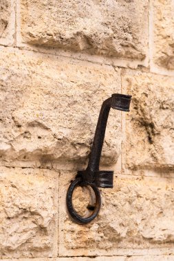 Metal kancalar desenli taş duvara karşı hizalanmış, kırsal tasarım ve işçilik sergiliyor.