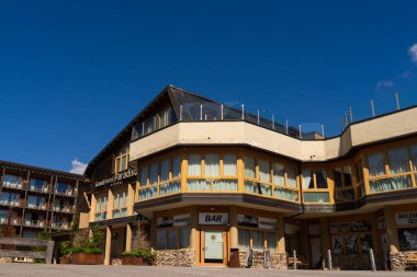 Passo Tonale, İtalya - 10.08.2024: Açık mavi gökyüzünün altında barı olan modern otel binası.