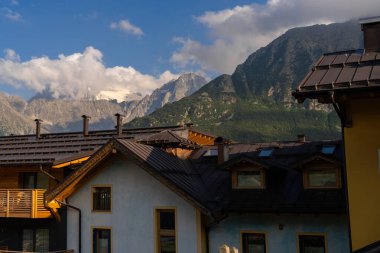 Passo Tonale, İtalya - 10.08.2024: Dağlık evler ve açık mavi gökyüzü manzaralı dağ manzarası.