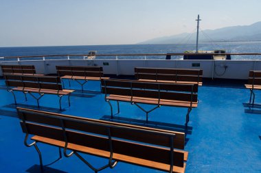 Sicilya, İtalya - 27.07.2024: Güneşli bir denizde güneşli bir günde bankları olan boş feribot güvertesi.