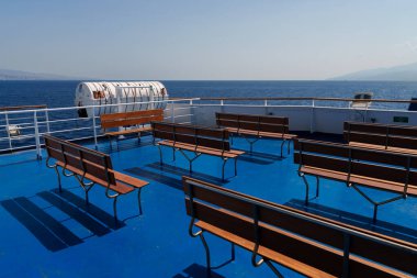 Sicilya, İtalya - 27.07.2024: Açık denizde açık bir günde bankları ve filikaları olan boş feribot güvertesi.