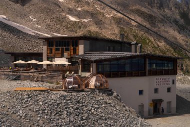 Passo Tonale, İtalya - 10.08.2024: Rifugio Capanna 'da açık hava yemekleri ve igloo tarzı pansiyonları olan dağ inzivası, manzaralı Alp manzarası.