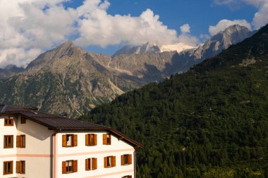Passo Tonale, İtalya - 10.08.2024: Alp manzaralı ve yemyeşil vadideki kır evi.