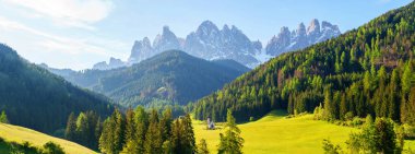 İtalya 'nın Dolomites kentindeki Funes Vadisi yakınlarında yemyeşil orman ve görkemli tepelerle nefes kesici dağ manzarası.