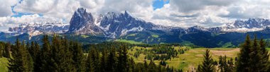 İtalya, Dolomites 'teki Funes Vadisi yakınlarında karlı tepeleri ve yemyeşil vadisi olan görkemli bir dağ manzarası..