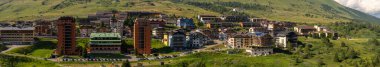 Passo Tonale, İtalya - 10.08.2024: Alp köyünün yemyeşil tepeleri ve manzaralı mimarisi.