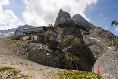 Passo Tonale, İtalya - 10.08.2024: Kayalık Alp manzarasındaki dağ teleferiği istasyonu.