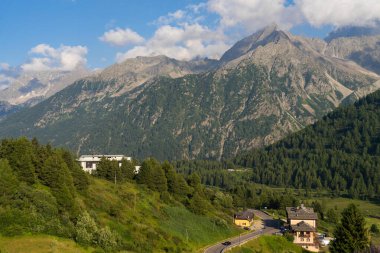 Passo Tonale, İtalya - 10.08.2024: Dağ manzaralı ve kırsal evlere sahip manzara dağları.