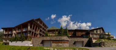 Passo Tonale, İtalya - 10.08.2024: Mavi gökyüzü ve kırsal mimarisi olan dağ beldesi.