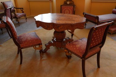 Villa Carlotta, İtalya - 24.03.2024: Tarihi Carlotta villasında klasik oturma alanı, ahşap masa ve lüks kırmızı döşemeli sandalyeler, kaliteli işçiliği ve dekoruyla klasik zarafet.