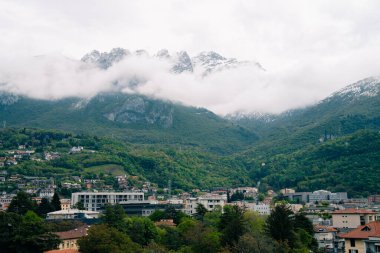 Lecco, İtalya - 19.05.2024: Serene dağ kasabası bulutlarla kaplı zirveler ve yemyeşil.
