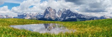 Karla kaplı dağlarla görkemli dağ manzarası ve İtalya 'nın Dolomites kentindeki Funes Vadisi yakınlarında sakin bir göl manzarası..