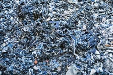 Paramparça kot kumaş kırıntıları. Sürdürülebilir moda üretiminde veya çevre dostu tekstil ürünlerinde yeniden kullanılmak üzere geri dönüştürülmüş eski mavi tekstil parçaları. Çiğ doku, makro çekim. Geri dönüştürülmüş kot