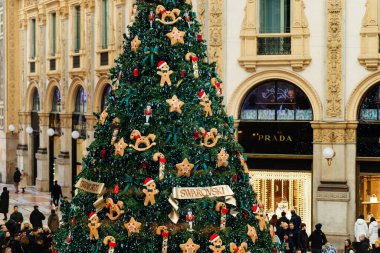Milan, İtalya - 18.12.2022: Zencefilli ekmekler, yıldızlar ve şenlikli süslerle süslenmiş büyük bir Noel ağacı. Parlak ışıklar ve dekorasyonlar, Victor Emmanuel 'in galerisindeki tatil atmosferi