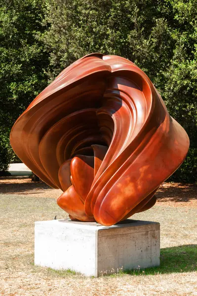 Floransa, İtalya - 30 Ağustos 2022: Parlak güneş ışığı altında Floransa 'nın Boboli Garden kentindeki beton bir kaide üzerinde canlı kırmızı, soyut heykel sergilendi