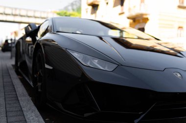 Milan, İtalya - 10.09.2022: Parlak siyah Lamborghini spor arabası şehir caddesine park edilmiş modern zarafeti yansıtıyor.