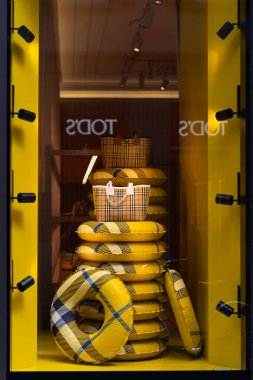 Milan, İtalya - 02.08.2023: Canlı sarı Burberry vitrininde yaz aksesuarları ve moda ilham kaynakları sergileniyor.