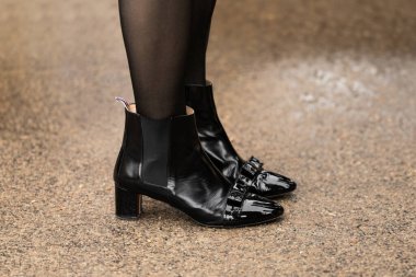 Paris, Fransa - 24 Ocak 2024: Asfaltta siyah çizmeler. Moda kadını kıyafet ayrıntıları, sokak tarzı..