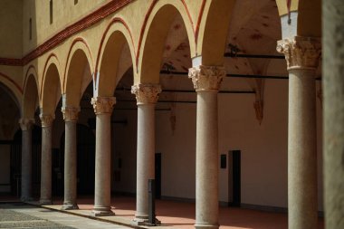 Milan, İtalya - 01.07.2024: Castello Sforzesco 'da tarihi kemerli koridorlarda sütunlar, loş ışıklar ve sıcak mimari tonlar