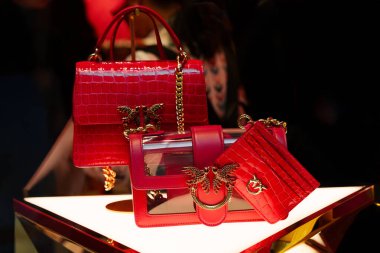 Milan, İtalya - 20.05.2024 Pinko mini aşk çantası. Altın aksan ve zincir kayışlarla süslenmiş parlak kırmızı el çantalarının yer aldığı lüks ekran.