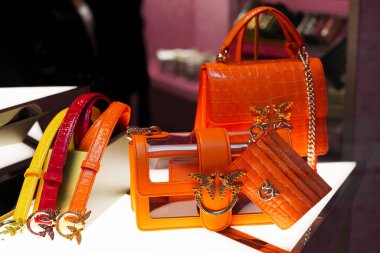Milan, İtalya - 20.05.2024 Pinko mini aşk çantası. Altın aksanlı ve zincir kayışlı parlak turuncu çantaların yer aldığı lüks ekran.