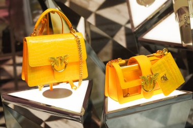 Milan, İtalya - 20.05.2024 Pinko mini aşk çantası. Altın aksanlar ve zincir kayışlarla süslenmiş parlak sarı el çantalarının yer aldığı lüks ekran.